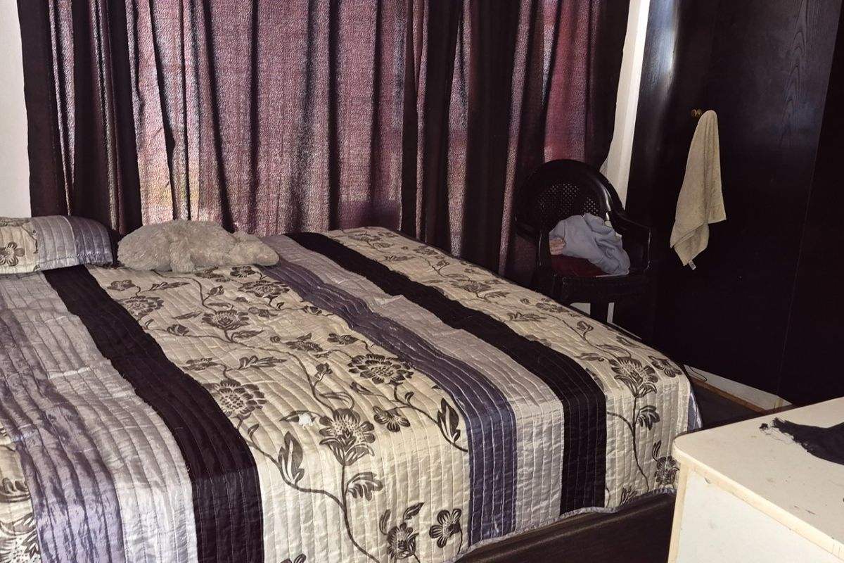 A bedroom featuring a built-in wardrobe and dark curtains, providing a functional sleeping space.