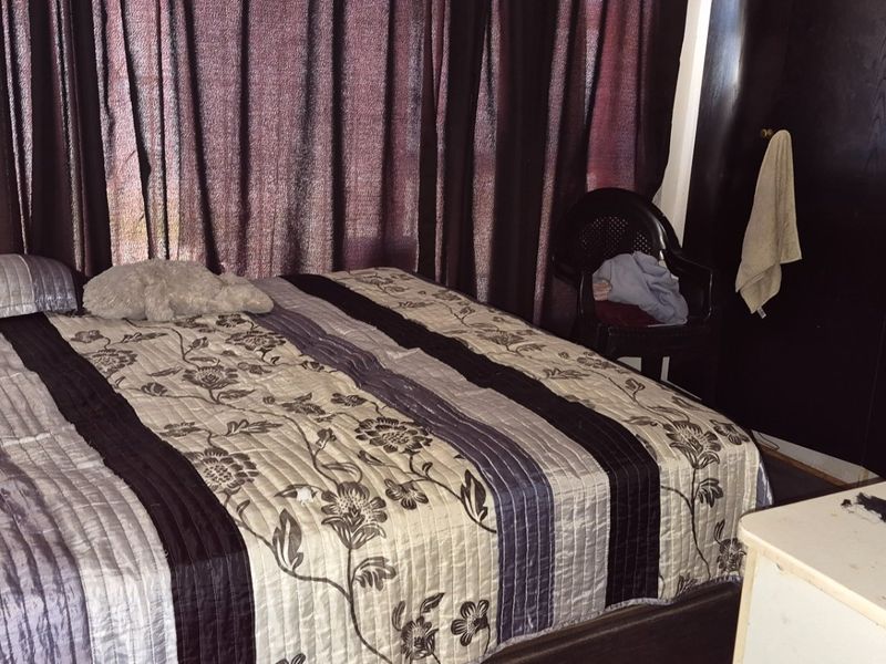 A bedroom featuring a built-in wardrobe and dark curtains, providing a functional sleeping space.