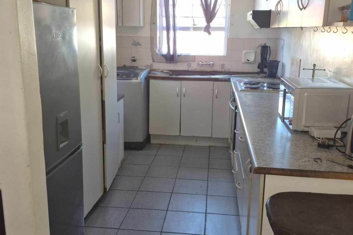 A functional kitchen featuring tiled flooring, laminate countertops, built-in cabinetry, and a tiled backsplash, offering potential for modernization and aesthetic updates.