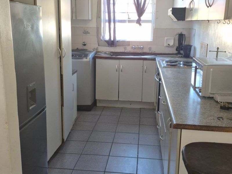A functional kitchen featuring tiled flooring, laminate countertops, built-in cabinetry, and a tiled backsplash, offering potential for modernization and aesthetic updates.
