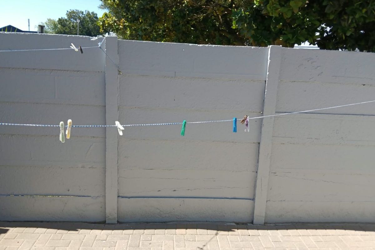 A rear outdoor area featuring a painted precast concrete boundary wall and paved patio surface.