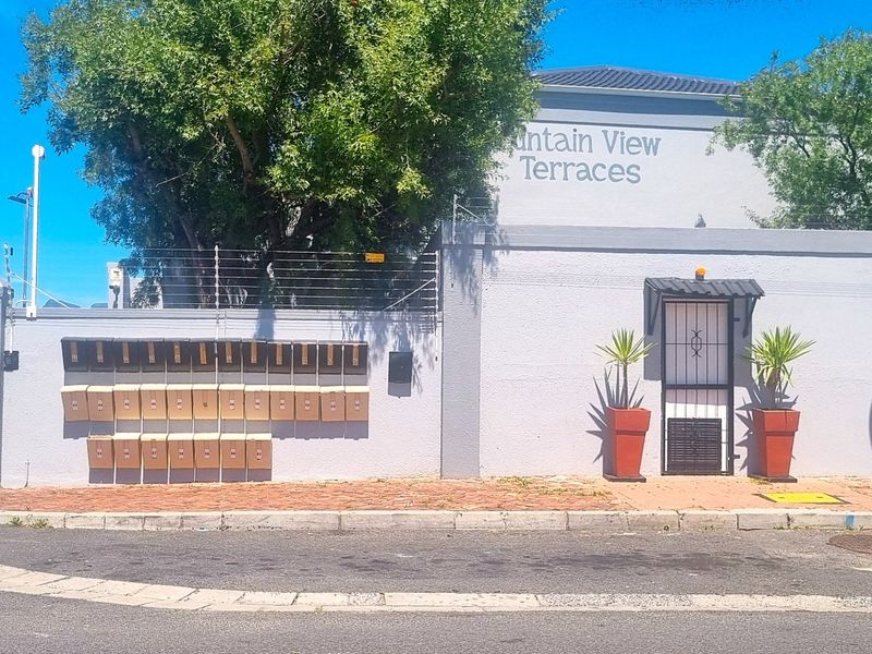 Front entrance view of Mountain View Terraces featuring a secure gated access point, boundary wall with electric fencing, and a row of post boxes.