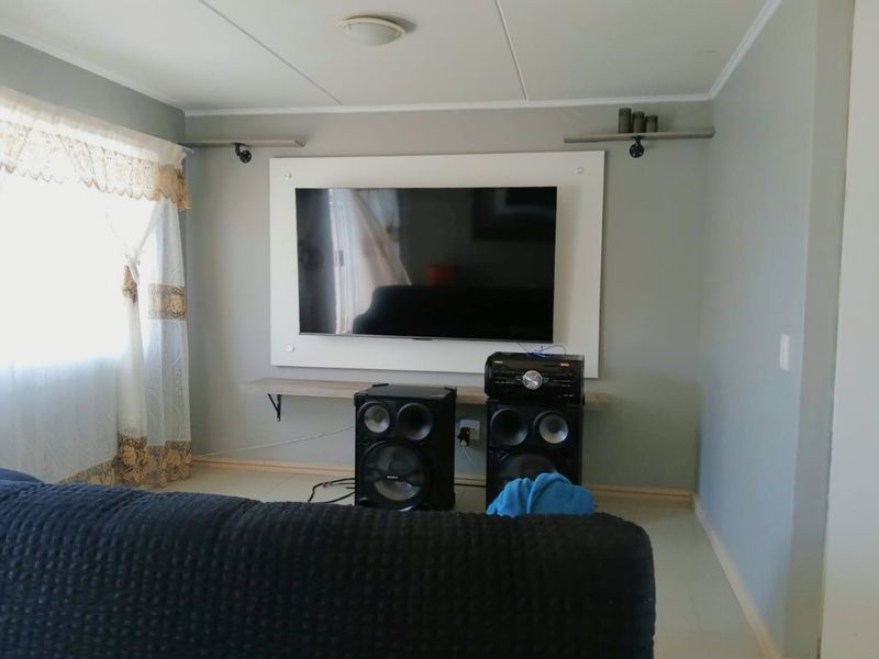 A living room featuring a wall-mounted television display unit with floating shelving and neutral wall tones.