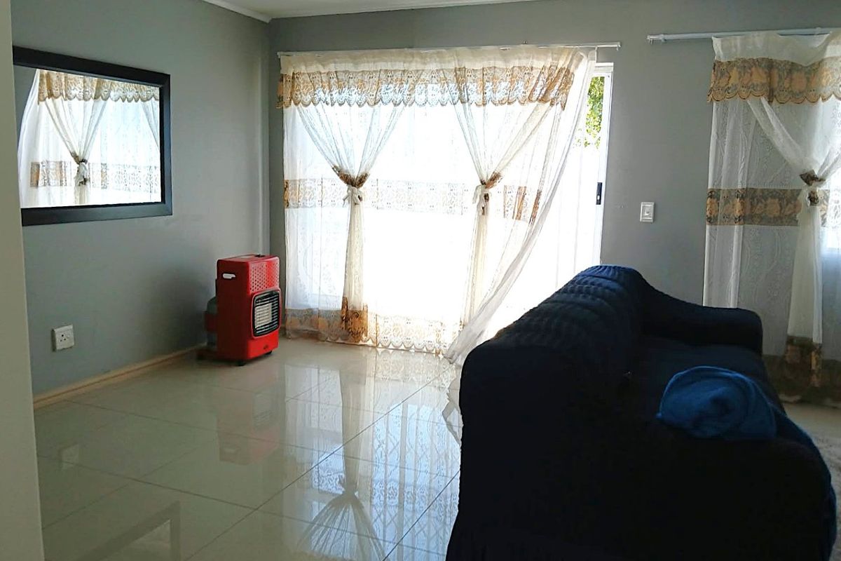 A living room featuring polished tiled flooring and a large sliding glass door providing natural light and access to the exterior.