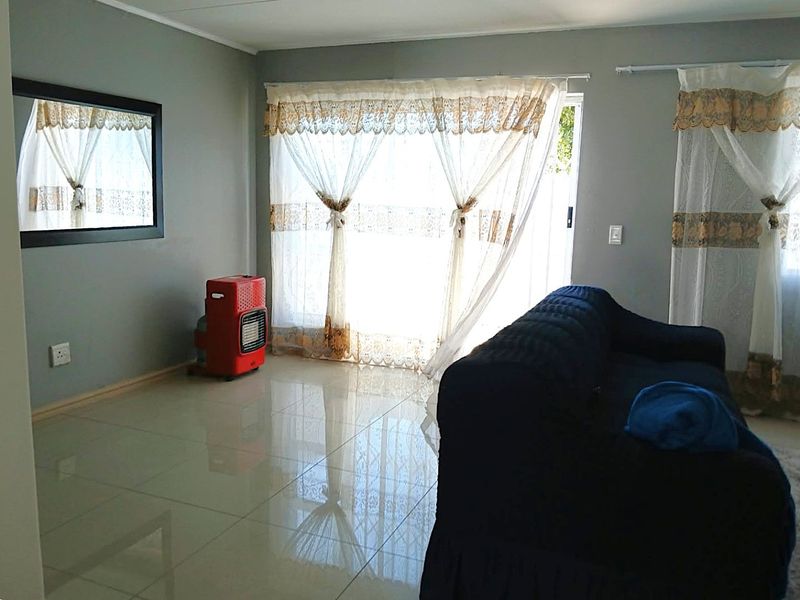 A living room featuring polished tiled flooring and a large sliding glass door providing natural light and access to the exterior.