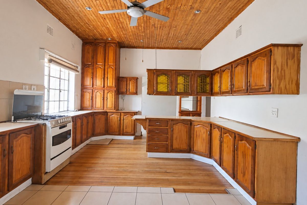 Spacious kitchen featuring extensive wooden cabinetry, a gas stove, timber ceiling, and a combination of tiled and timber flooring.