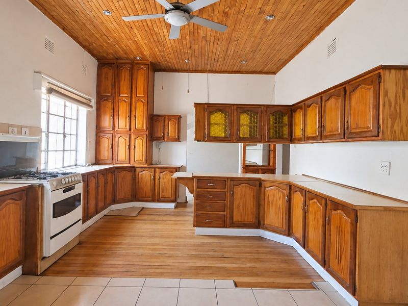 Spacious kitchen featuring extensive wooden cabinetry, a gas stove, timber ceiling, and a combination of tiled and timber flooring.