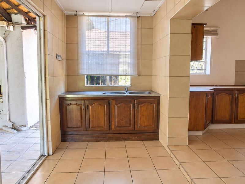 A functional kitchen featuring wooden cabinetry, tiled flooring, and a freestanding stove, with direct access to an outdoor patio area.