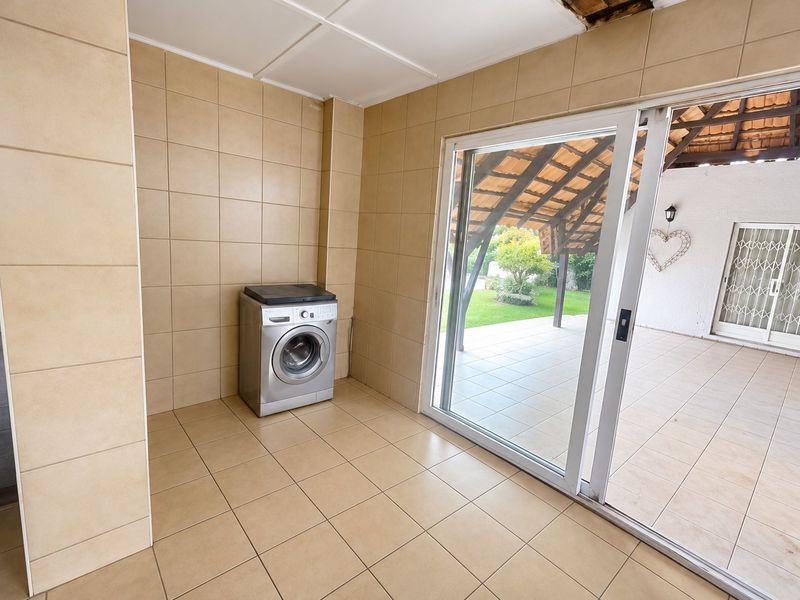 A tiled laundry area featuring a sliding glass door leading to a covered patio, with visible ceiling damage requiring repair.
