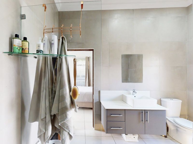 Modern bathroom featuring a floating vanity with a vessel sink, glass shower screen, and neutral wall and floor tiling.