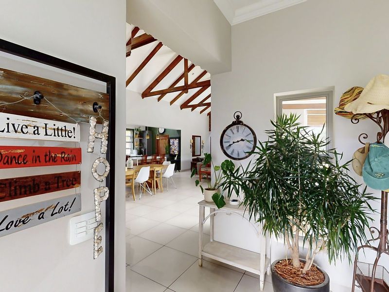 An open-plan living area featuring high vaulted ceilings with exposed timber trusses and neutral tiled flooring, creating a bright and spacious atmosphere.