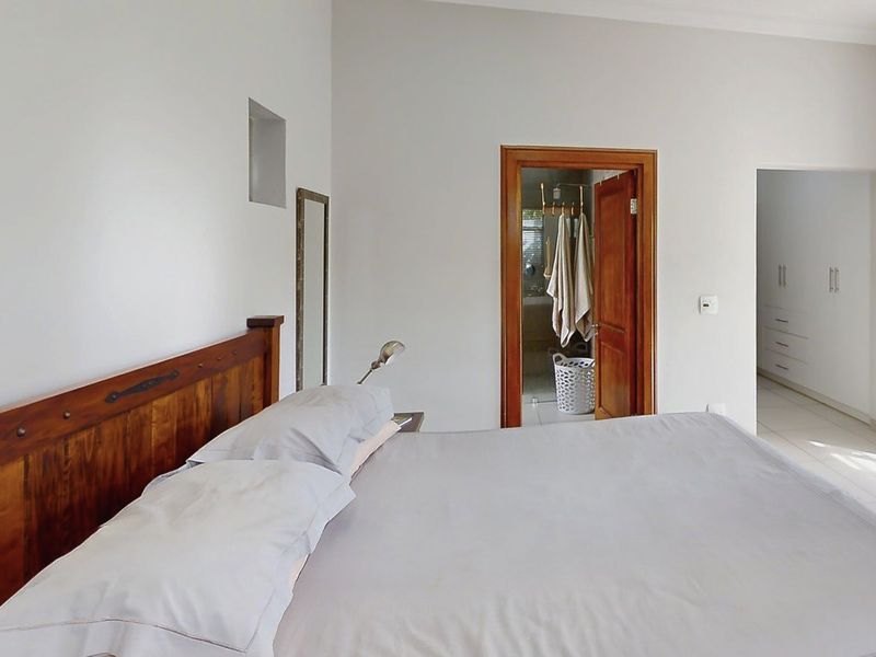A well-maintained bedroom featuring tiled flooring, built-in cupboards, and direct access to an en-suite bathroom through a wooden door frame.