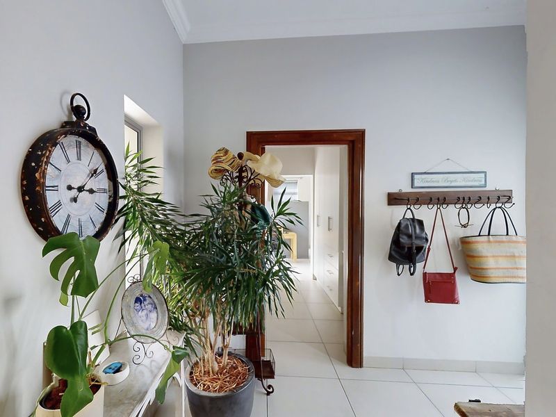 A bright and well-maintained hallway featuring neutral tiled flooring, clean white walls, and classic coving, providing a welcoming transition between living spaces.