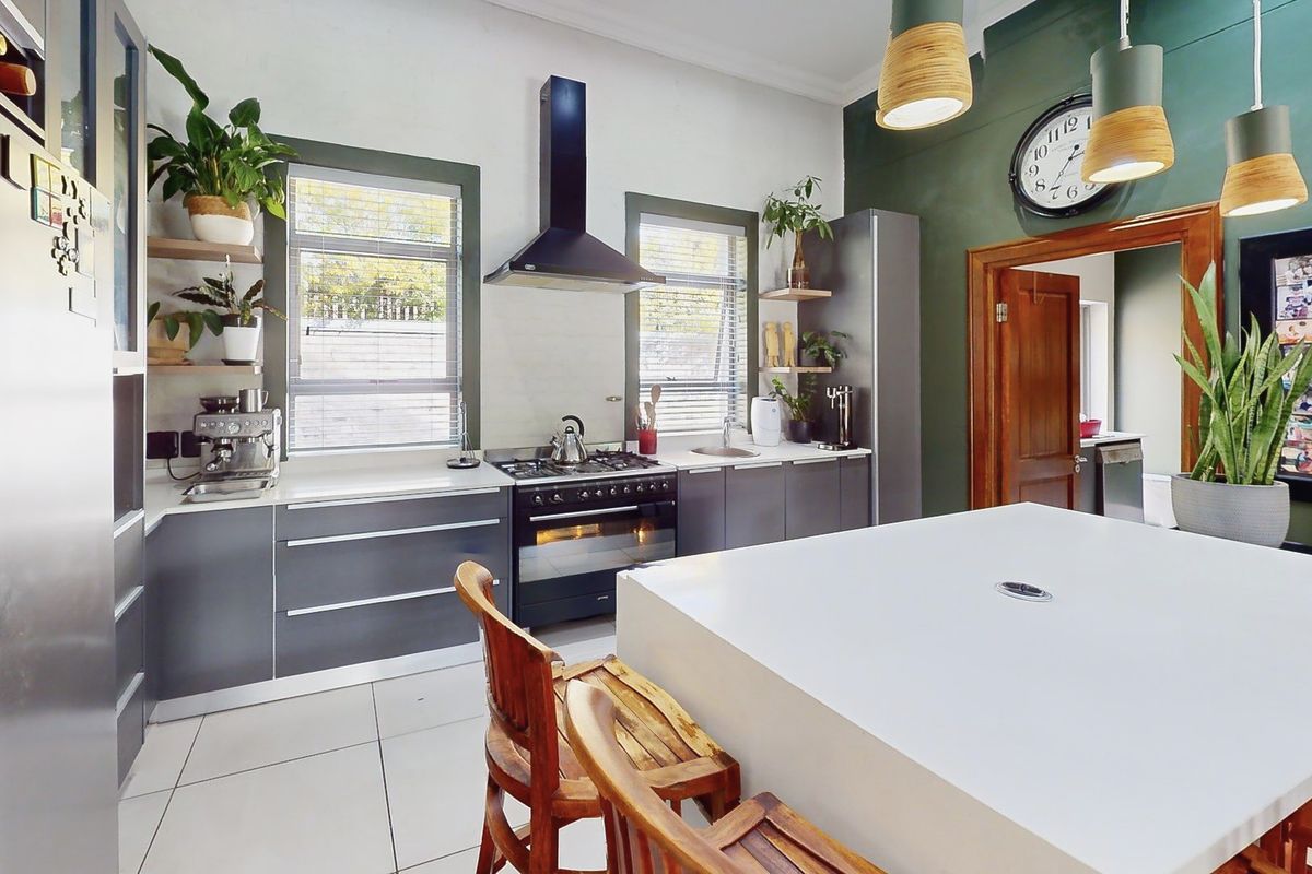Modern kitchen featuring dark grey cabinetry, stone countertops, a gas stove with extractor fan, and tiled flooring, complemented by a central island.