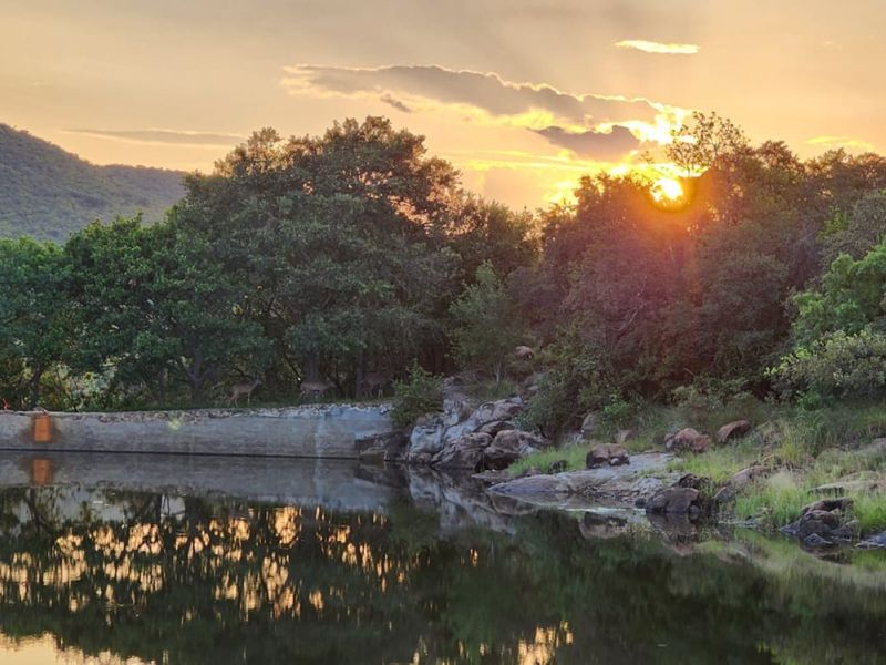 A scenic view of a natural water feature and surrounding landscape at sunset, showcasing the tranquil environment of the vacant residential land.