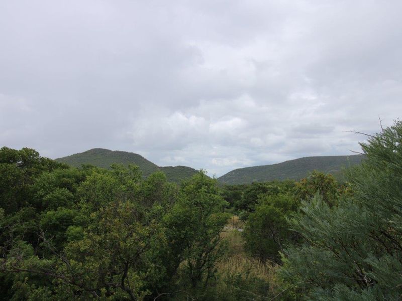 A scenic view of the surrounding natural landscape, featuring rolling hills and dense indigenous vegetation.