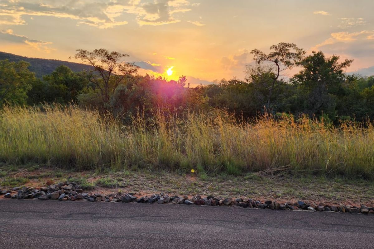 A scenic view of the natural landscape and sunset from the roadside of the vacant residential property.