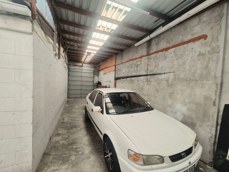 A functional garage space featuring concrete block walls, a corrugated metal roof with integrated skylights, and a secure sectional garage door.