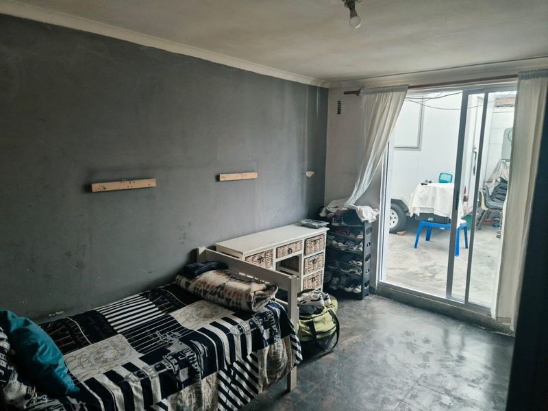 A bedroom featuring concrete flooring and a sliding glass door providing access to an outdoor area.