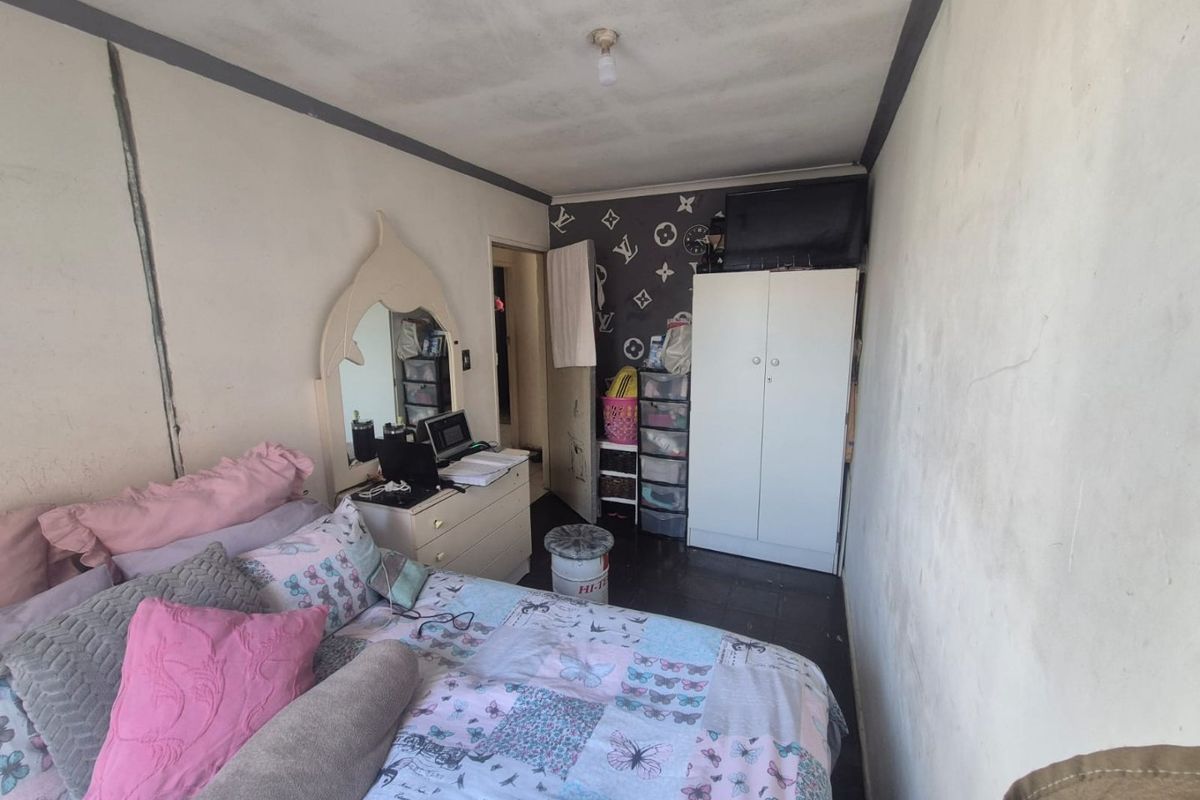 A bedroom featuring a built-in wardrobe, requiring cosmetic updates to the wall and ceiling finishes to improve the overall condition.