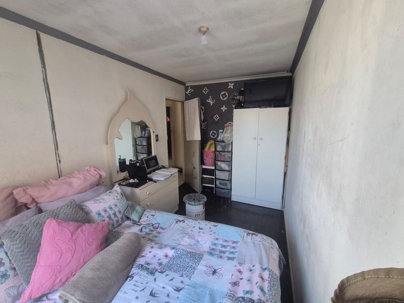 A bedroom featuring a built-in wardrobe, requiring cosmetic updates to the wall and ceiling finishes to improve the overall condition.