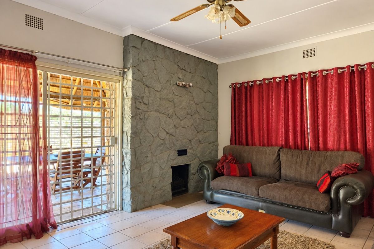 Living room featuring a prominent stone fireplace, tiled flooring, and a sliding glass door providing access to an outdoor patio area.