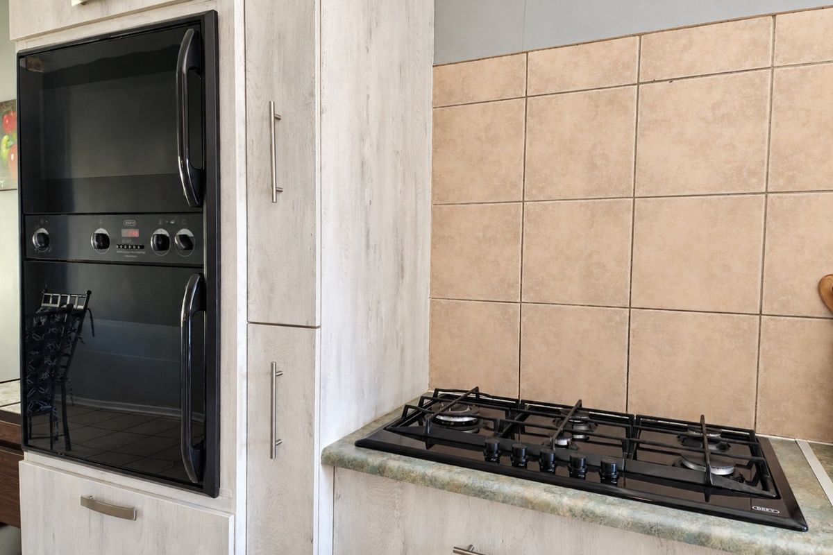 A functional kitchen area featuring a built-in oven, gas hob, light-toned cabinetry, and a tiled backsplash.
