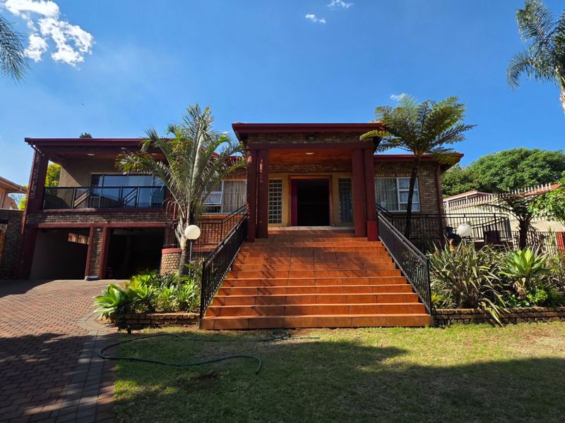 Front elevation of a multi-level brick house featuring a prominent tiled staircase leading to the main entrance, a paved driveway, and an integrated garage.
