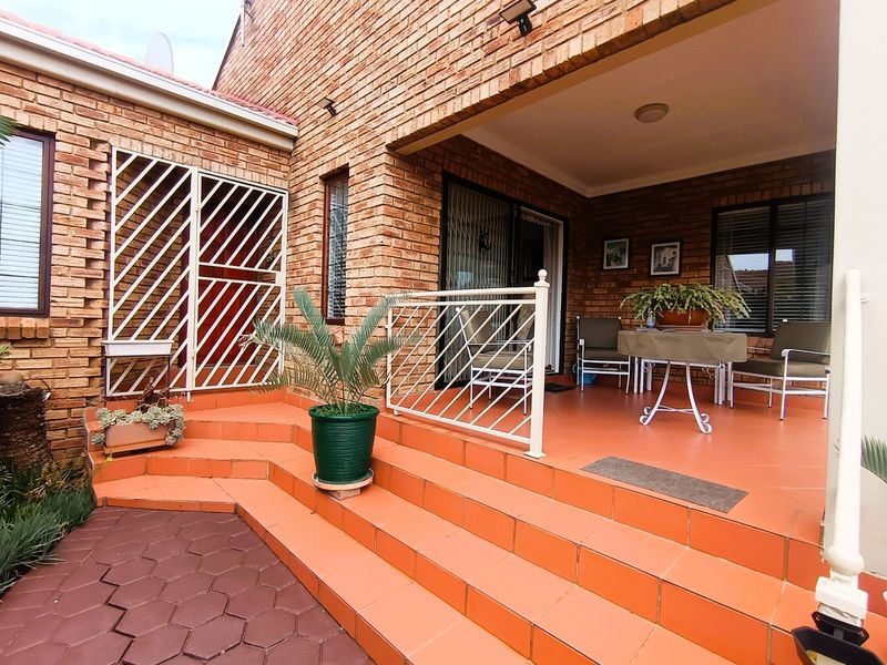 Covered patio area featuring face brick walls, tiled flooring, and a metal balustrade, providing a functional outdoor space for relaxation.