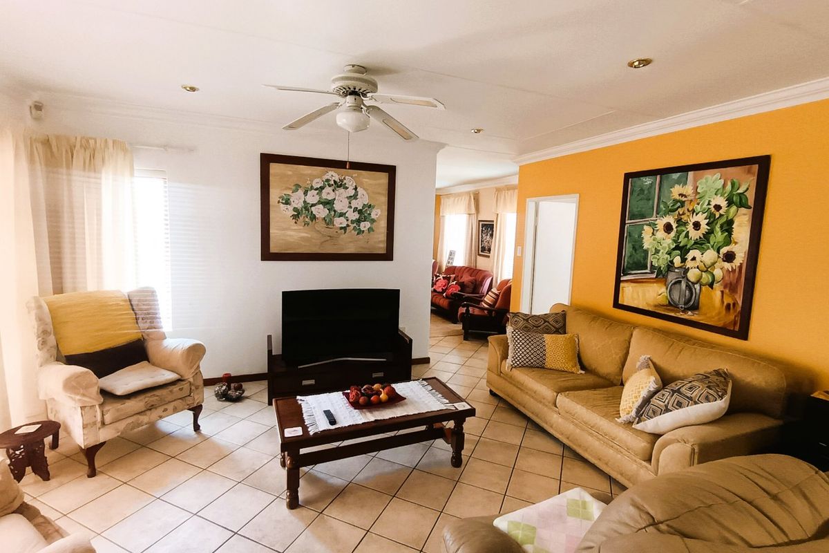 Spacious living room featuring tiled flooring, recessed lighting, and a ceiling fan, with a bright accent wall and neutral decor.