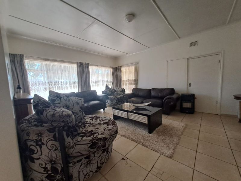 A spacious living room featuring tiled flooring and a traditional ceiling, offering a blank canvas for modern updates and interior design improvements.