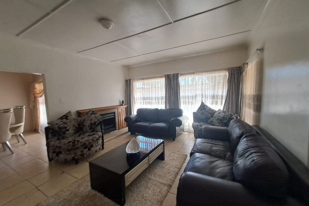 A spacious living room featuring tiled flooring and a built-in fireplace, offering a comfortable area for relaxation and family gatherings.