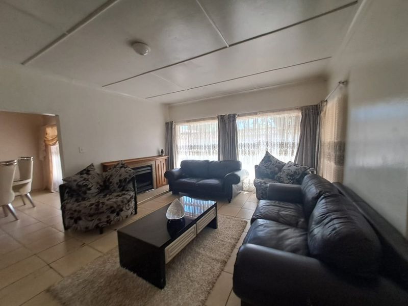 A spacious living room featuring tiled flooring and a built-in fireplace, offering a comfortable area for relaxation and family gatherings.