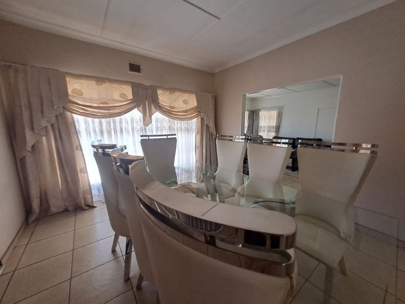 A dining room featuring tiled flooring and a ceiling vent, with an open-plan connection to an adjacent living area.