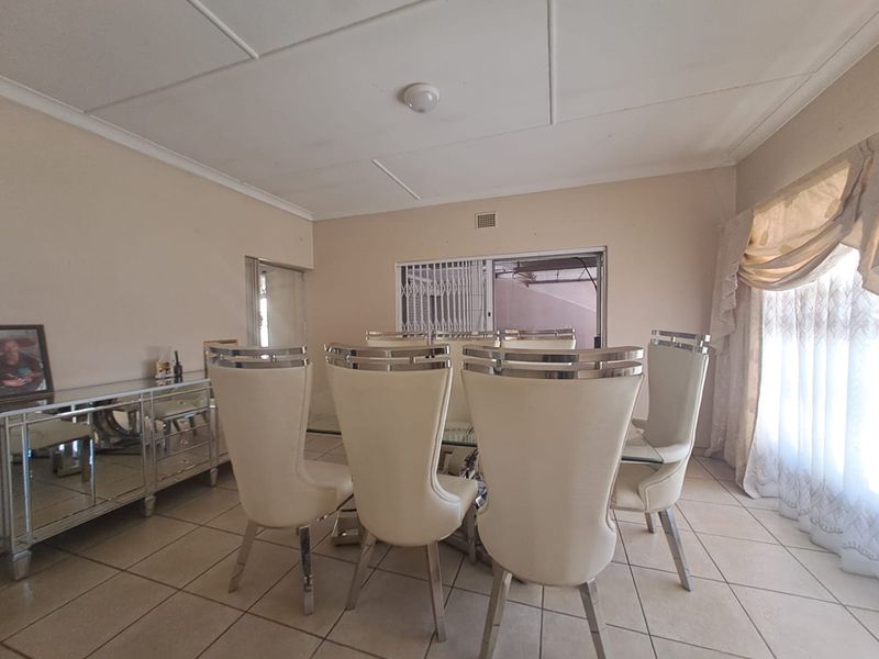 A dining room featuring tiled flooring, a ceiling ventilation grille, and a sliding security gate leading to the exterior.