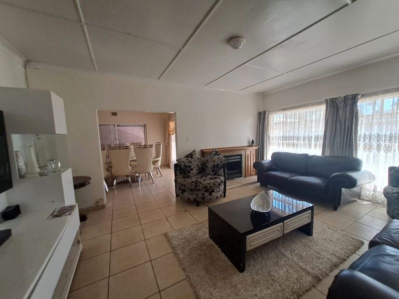 Spacious open-plan living and dining area featuring tiled flooring, a built-in fireplace, and large windows allowing for natural light.