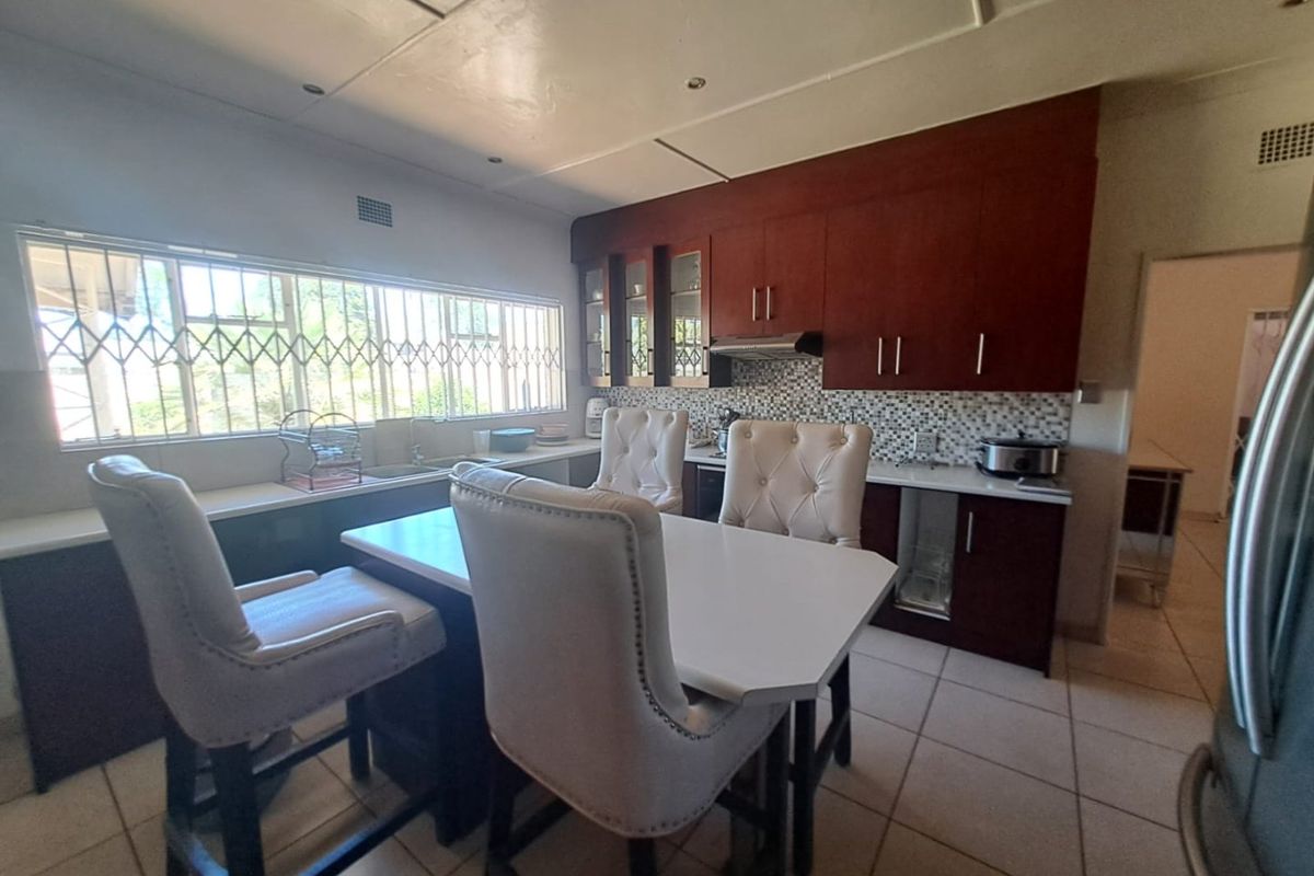 A functional kitchen featuring dark wood cabinetry, a tiled backsplash, built-in extractor fan, and tiled flooring with ample natural light.