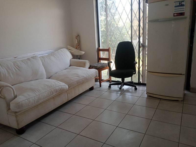 A living area featuring tiled flooring and a sliding glass door with a security gate, providing access to the exterior.