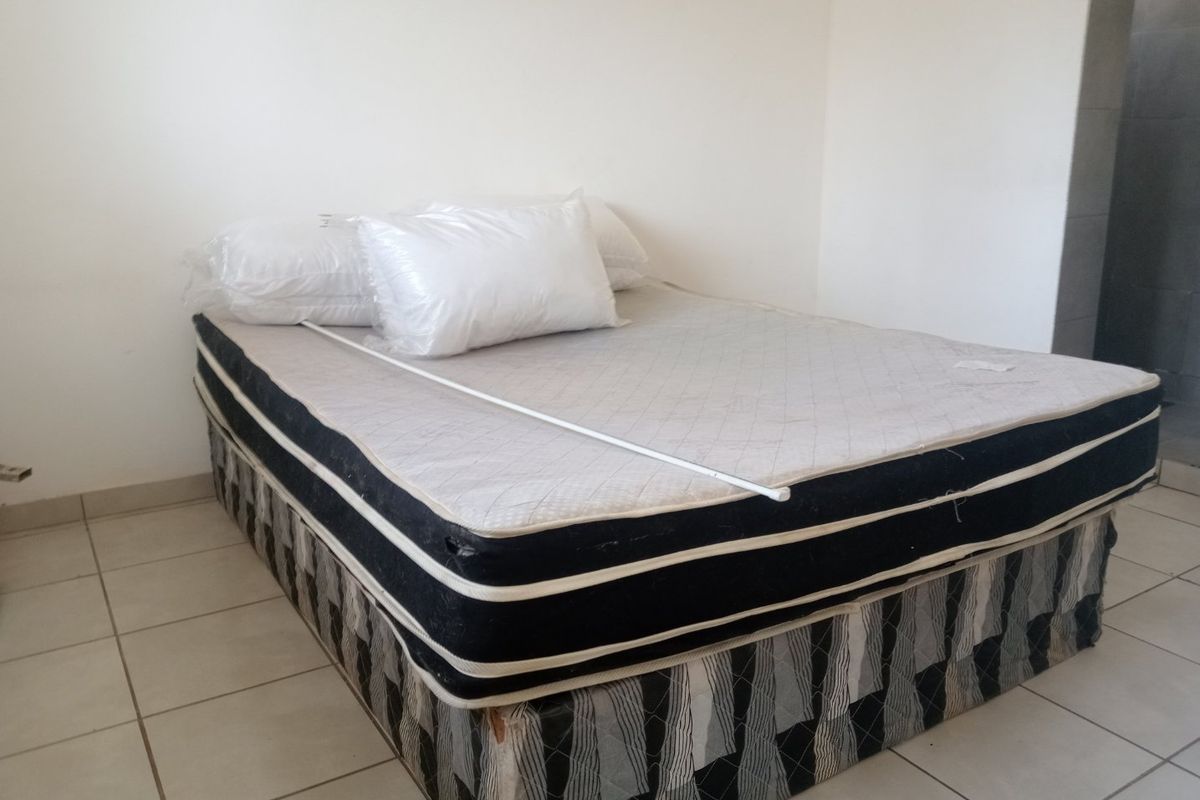 A simple bedroom featuring tiled flooring and neutral wall finishes, providing a blank canvas for potential interior design updates.