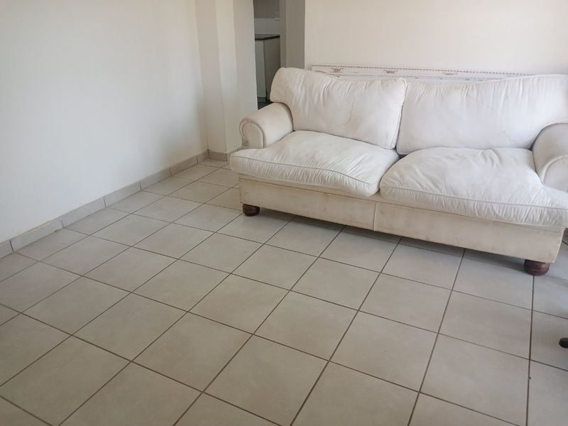 A living room area featuring neutral ceramic floor tiles and plain white walls, offering a blank canvas for interior design updates.