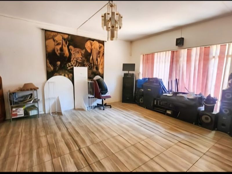 A spacious living room featuring tiled flooring and a central ceiling light fixture, offering a blank canvas for potential interior design updates.