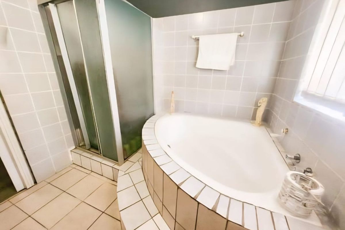 A functional bathroom featuring a built-in corner bathtub and a separate tiled shower enclosure with a sliding door.