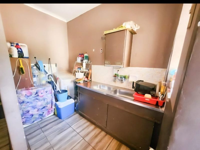 A functional laundry area featuring a stainless steel sink, built-in cabinetry, and tiled flooring, providing essential utility space for the home.