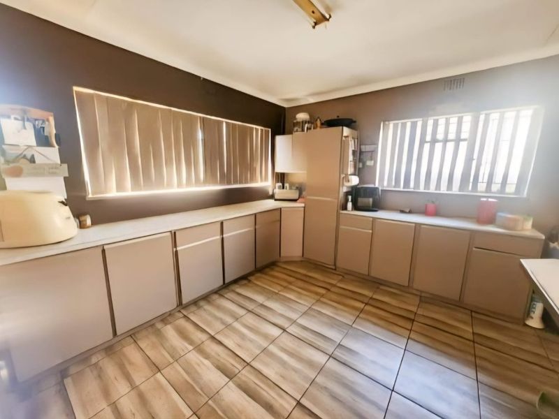 A functional kitchen featuring extensive laminate cabinetry, ample countertop workspace, and tiled flooring, offering a blank canvas for modern renovation and aesthetic updates.
