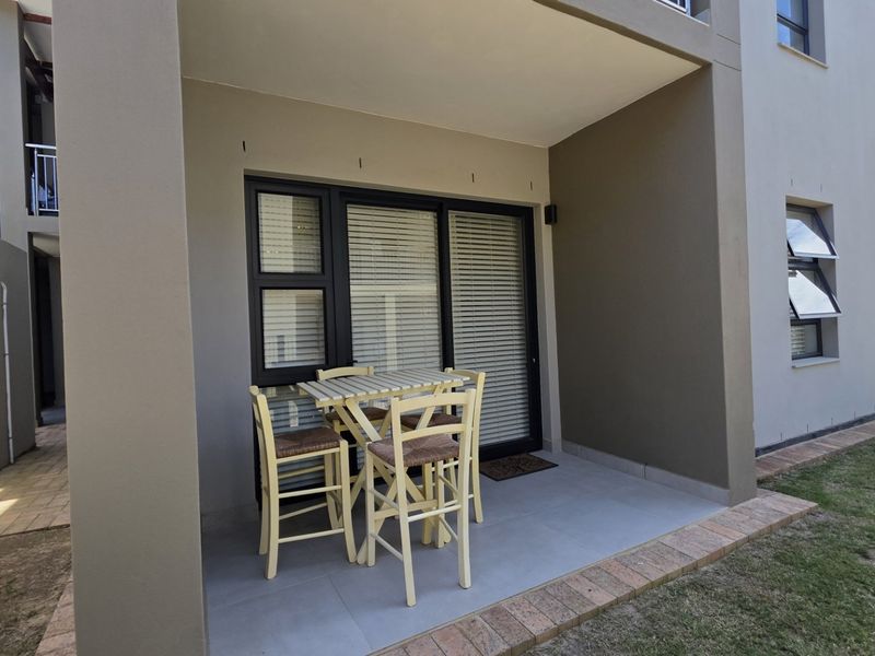 A covered patio area featuring tiled flooring and access to the interior through a sliding glass door.