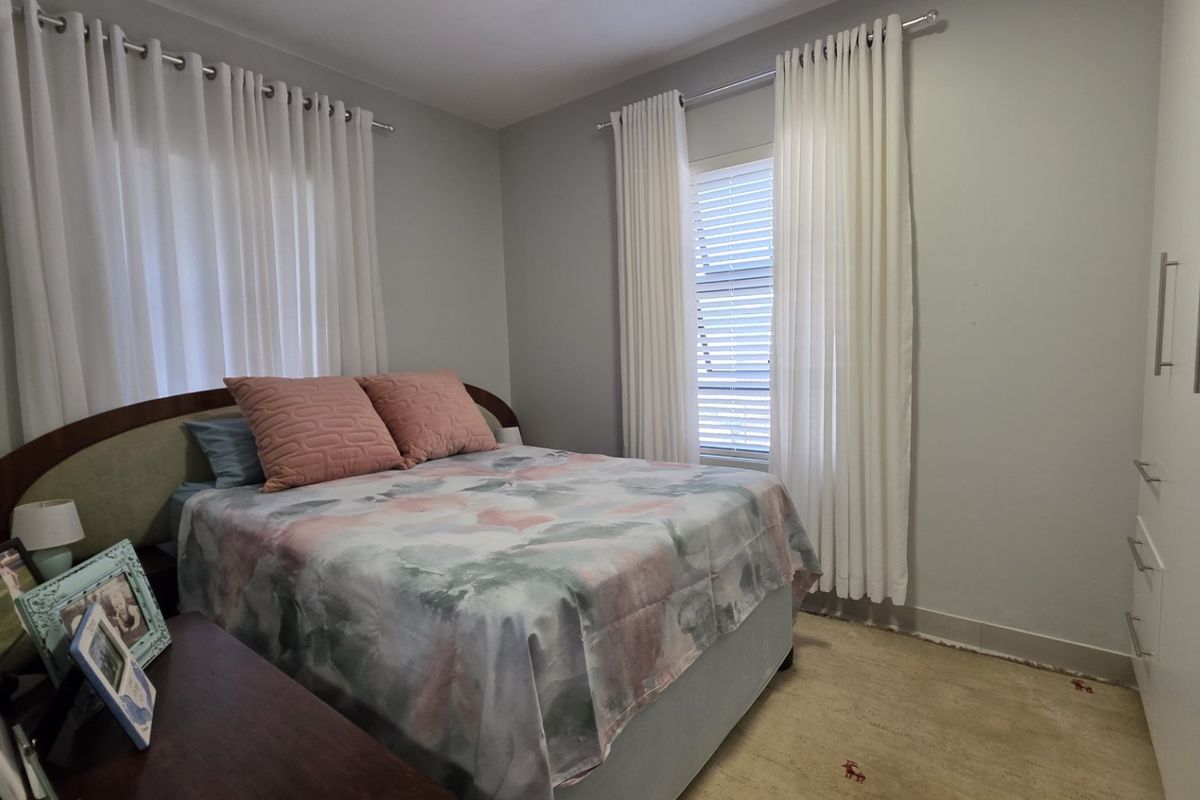 A well-maintained bedroom featuring neutral wall tones, built-in wardrobe storage, and dual window treatments.