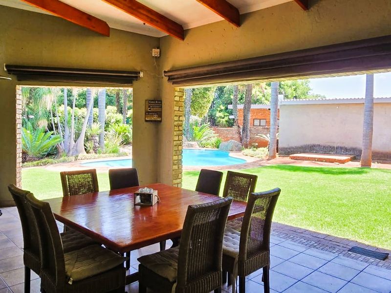 Spacious covered patio featuring exposed timber beams and tiled flooring, offering seamless indoor-outdoor flow to the garden and swimming pool area.
