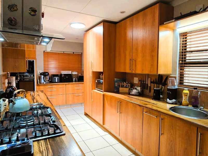 A well-appointed kitchen featuring warm wooden cabinetry, solid wood countertops, a gas hob with extractor, and tiled flooring.