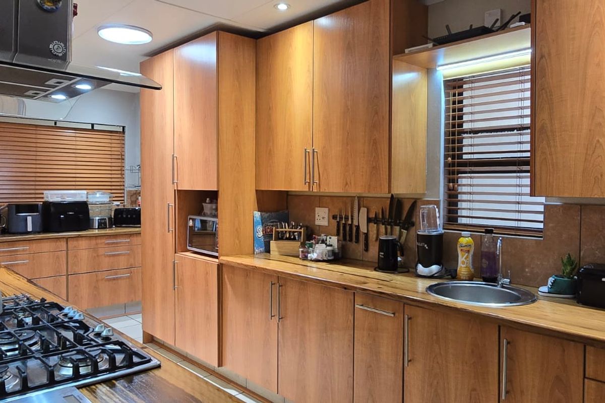 A well-maintained kitchen featuring warm wooden cabinetry, matching wooden countertops, a gas hob with extractor, and integrated stainless steel sink.