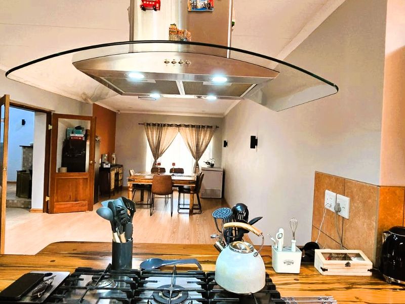 Open plan kitchen and dining area featuring wooden countertops, a gas hob, and a stainless steel extractor fan, flowing into a connected living space.